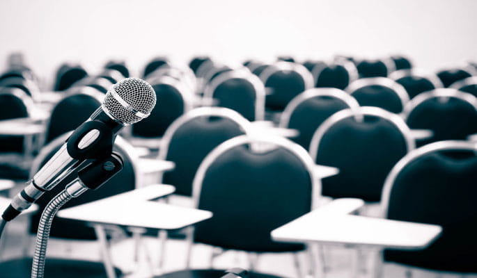 Image of a microphone stand in front of chairs