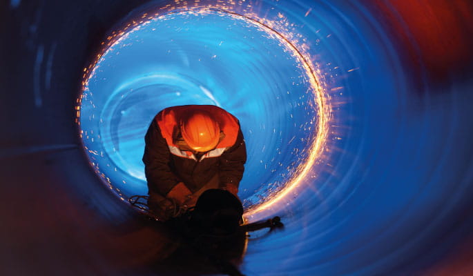Image of a construction worker welding a pipe