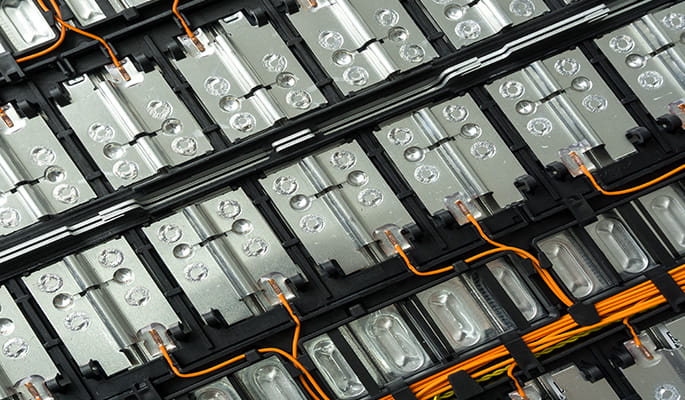 A close-up of a silver and black battery storage board with orange wires