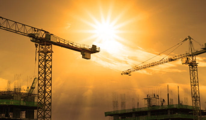 Image of two cranes over a building construction site 