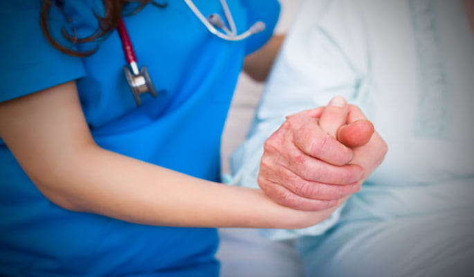 Image of a patient and nurse holding each others hand