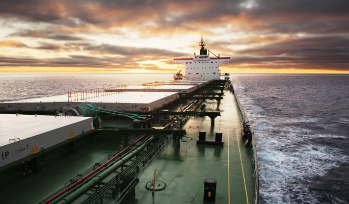 Image of a large ship at sea sailing towards the sunset 