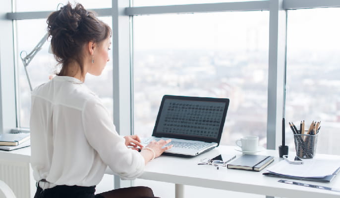 Business woman sitting at a desk using a laptop in an office