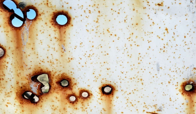 Image of a sheet of metal containing rusty bullet holes