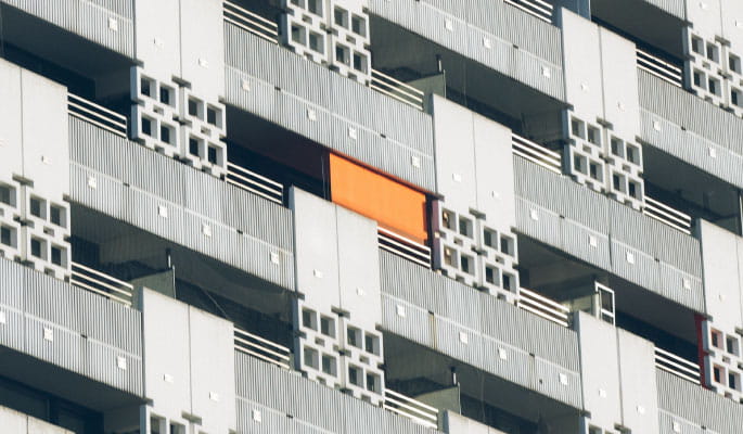 Image of a modern residential block with a single orange sunscreen on one of the balconies 